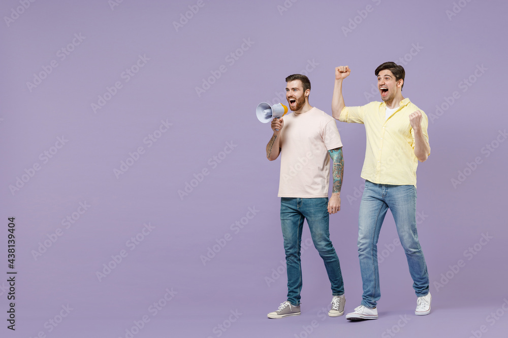 Full length young men friends together in t-shirt scream shout hot news in megaphone doing winner gesture clench fist isolated on purple background studio portrait People lifestyle friendship concept.