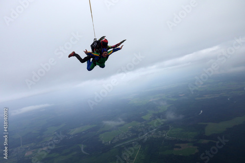 Skydiving. Tandem jump is in the cloudy sky.