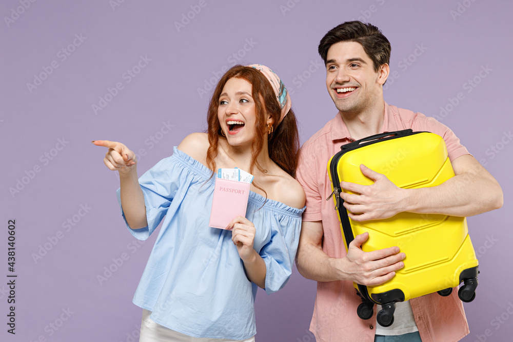 Two excited traveler tourist woman man couple in shirt hold suitcase passport ticket point finger aside isolated on purple background Passenger travel abroad weekend getaway Air flight journey concept Two excited traveler tourist woman man couple in shirt hold suitcase passport ticket point finger aside isolated on purple background Passenger travel abroad weekend getaway Air flight journey concept