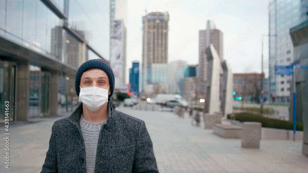 SARS-CoV-2 COVID-19 Coronavirus Pandemic Outbreak: Man Standing in Surgical Face Mask in City Downtown Street and Looks to Camera. Picture with Copy Space SARS-CoV-2 COVID-19 Coronavirus Pandemic Outbreak: Man Standing in Surgical Face Mask in City Downtown Street and Looks to Camera. Picture with Copy Space