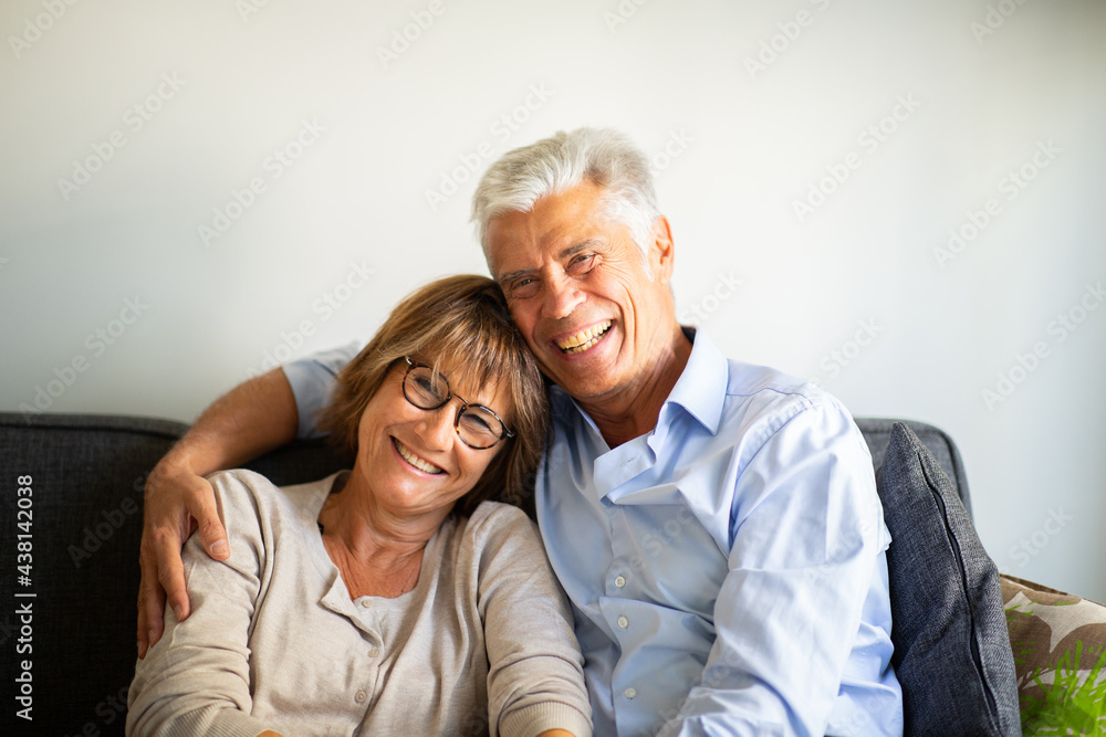 Close up smiling happy older couple sitting on sofa together Close up smiling happy older couple sitting on sofa together