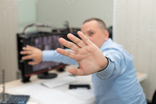 man outstretched hand and showing stop hand sign. Security guard in surveillance room. refusing or forbidding photos. Surveillance, control, safety of private property concept. blurred background