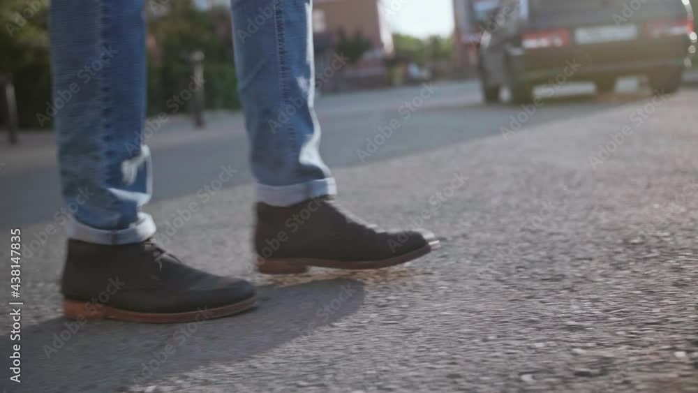 A man walks down the street at sunset with a close-up of his feet A man walks down the street at sunset with a close-up of his feet