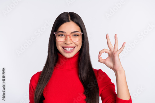 Photo of young smiling good mood charming asian girl in glasses show okay sign isolated on grey color background