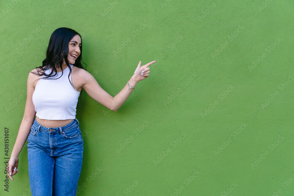 Cheerful teen pointing with finger on green background Cheerful teen pointing with finger on green background
