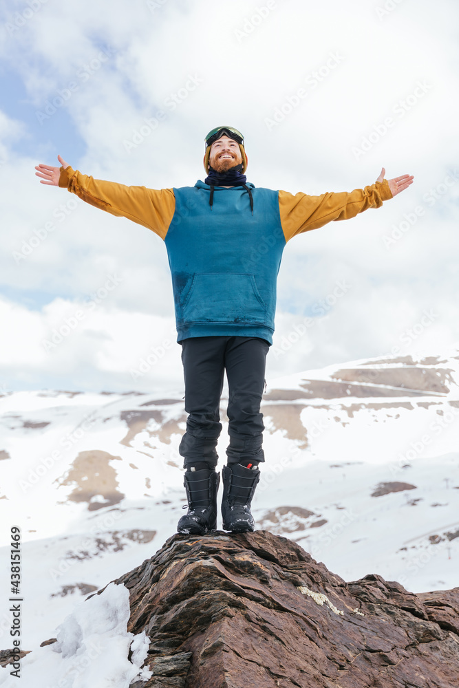 Smiling sportsman with outstretched arms on ridge in winter Smiling sportsman with outstretched arms on ridge in winter