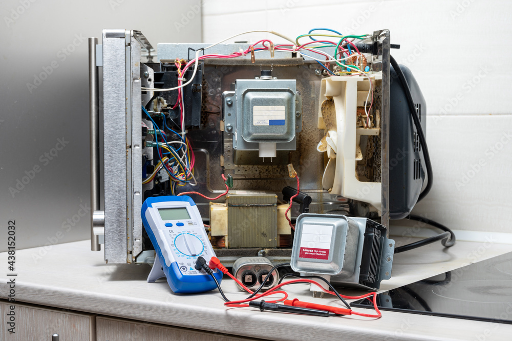 New magnetron, capacitor and tester next to the disassembled microwave