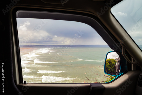 Van window overlooking Saunton Sands beach, with surfers in the water