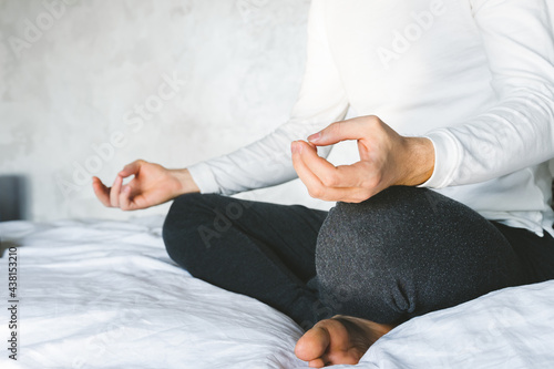 Man meditating in lotus position on bed.  Focus on incense stick and smoke. Unrecognizable yoga practitioner in the background. Relax after Yoga training © Natallia