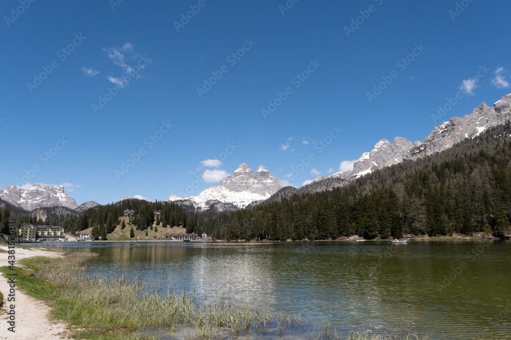 Misurina, Italy - May 31, 2021: The fabulous alpine lake in the Dolomites. Boat on the water. Lovely and relaxing place in the Italian Alps. Reflections in the rippled water. Sunny spring day.