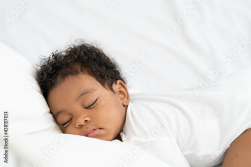 black african american baby sleeping on a white mattress.