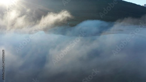 A  flight in the misty morning air above the waters of still lake Nerde Fiplingvatnet in Norway. Sunrays are expanding through the air, dramatically illuminating 
floating fog. photo