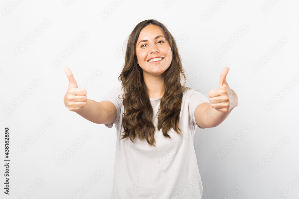 Portrait of amazed smiling woman showing thumbs up over white background Portrait of amazed smiling woman showing thumbs up over white background