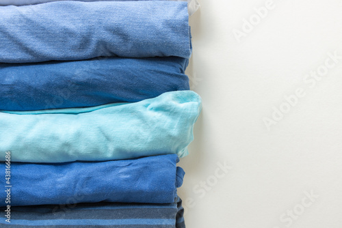 various shades of blue tee or t-shirts or undershirts rolled and folded on white