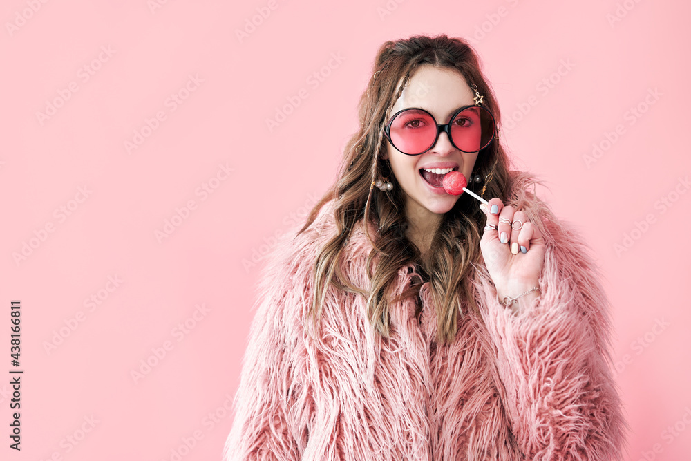 Fashion portrait of pretty hipster woman holding lollipop and looking to camera