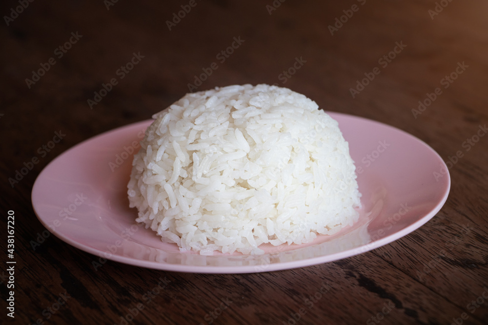 Steam white jasmine rice on pink plate on wooden table. Cooked jasmine rice is a main dish in asia and specially in Thailand. Steam white jasmine rice on pink plate on wooden table. Cooked jasmine rice is a main dish in asia and specially in Thailand.