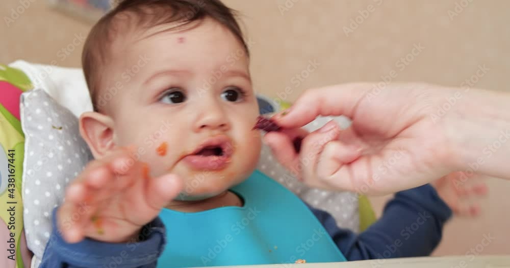 Mom feeds the boy with a spoon and hand, family food and parenthood concept. first complementary foods and self-feeding Mom feeds the boy with a spoon and hand, family food and parenthood concept. first complementary foods and self-feeding