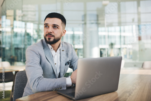Content young businessman working on laptop in modern business center