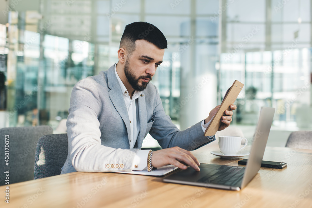 Serious businessman with notepad working on laptop Serious businessman with notepad working on laptop