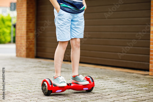 Close-up of kid boy on hover board. Child driving modern balance hoverboard. Excercise and sports for children, outdoor activity for young kids. photo