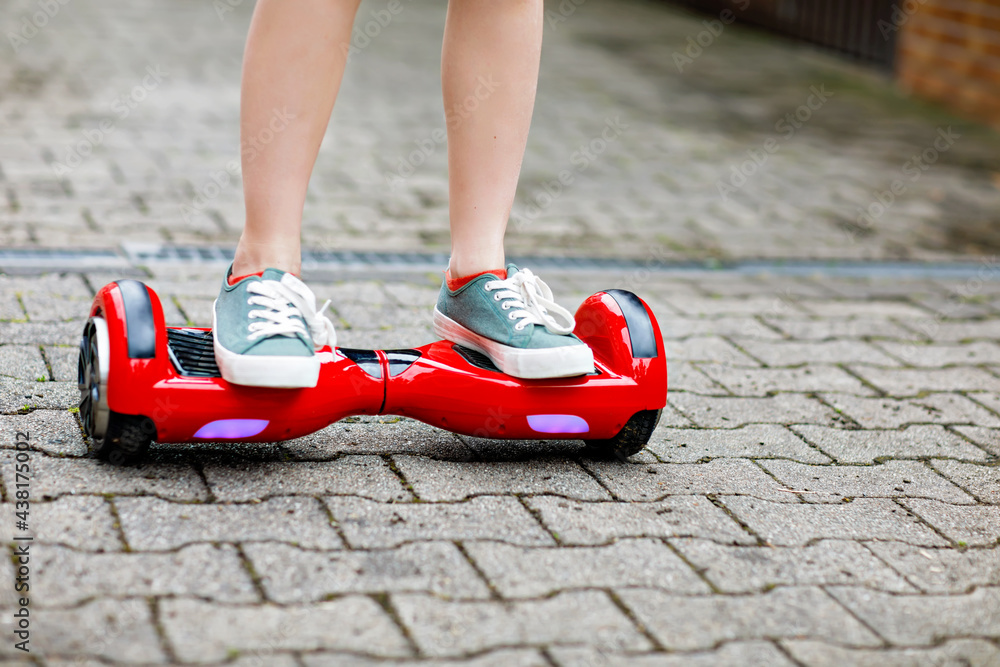 Close-up of kid boy on hover board. Child driving modern balance hoverboard. Excercise and sports for children, outdoor activity for young kids.