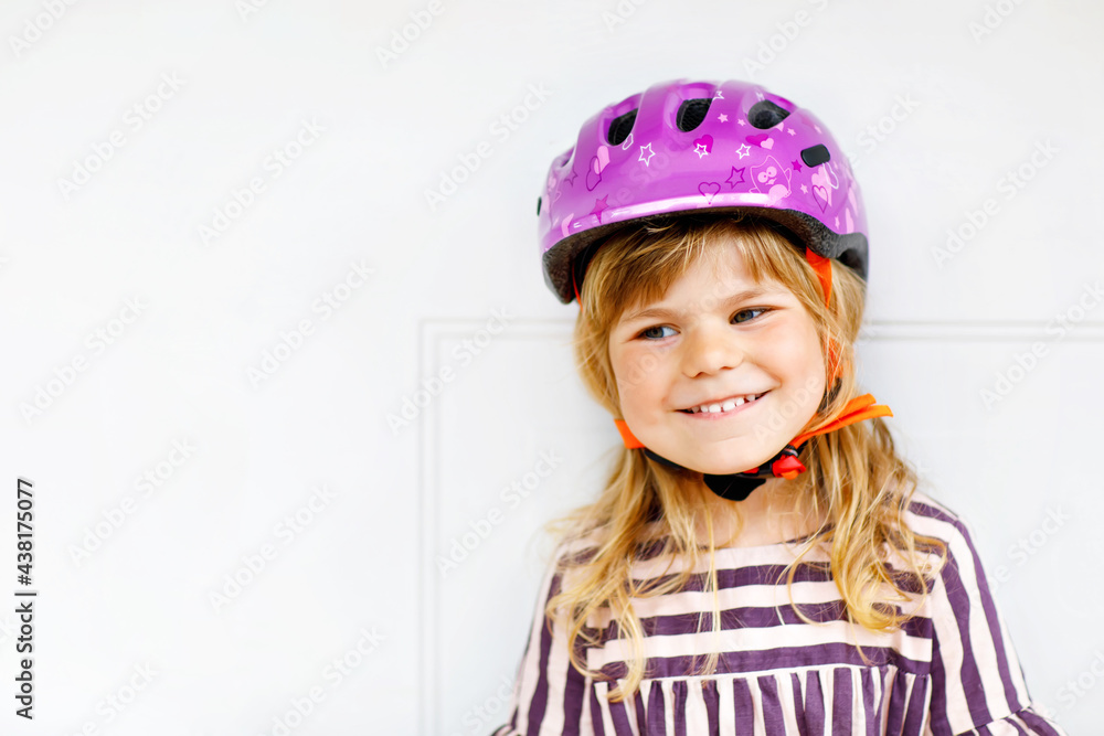 Portrait of happy smiling preschool girl with bycicle helmet on head. Cute toddler child. Safe bike driving with children concept. Safety helmet for kids Portrait of happy smiling preschool girl with bycicle helmet on head. Cute toddler child. Safe bike driving with children concept. Safety helmet for kids