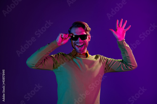 Photo portrait of smiling man wearing sunglass waving hands isolated on violet color background