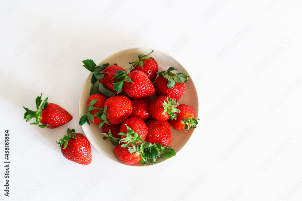 Strawberry berry with green leaf in a plate, isolated on a white background, white table. berries and food Strawberry berry with green leaf in a plate, isolated on a white background, white table. berries and food