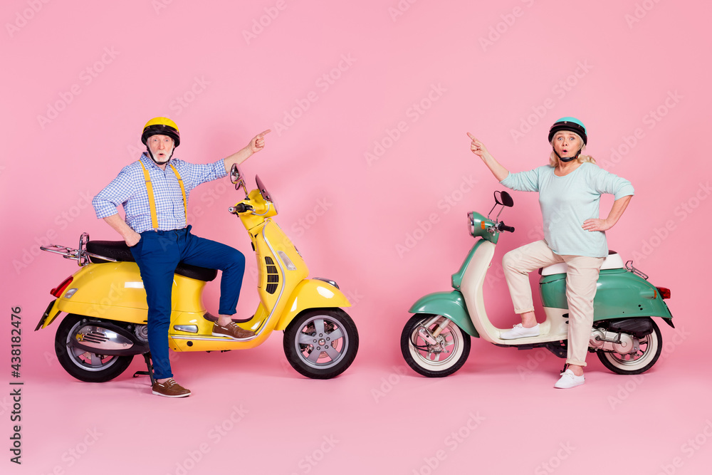 Profile photo of cute senior husband wife driving motorbike dressed helmets pointing empty space isolated pink color background