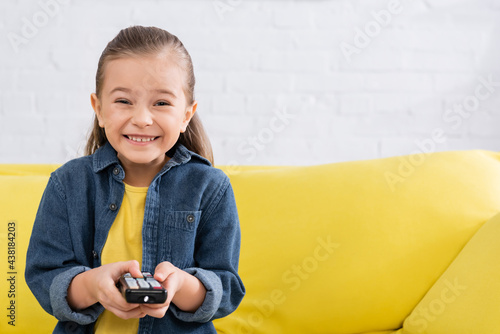 Happy girl holding remote controller and looking at camera