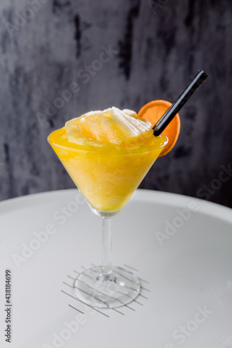 Glass of exotic cocktail with straw and peice of orange photo