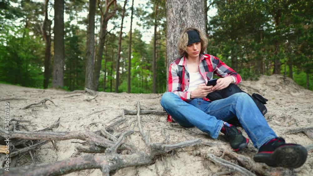 Male tourist with smartphone resting in the woods. Male tourist with smartphone resting in the woods.