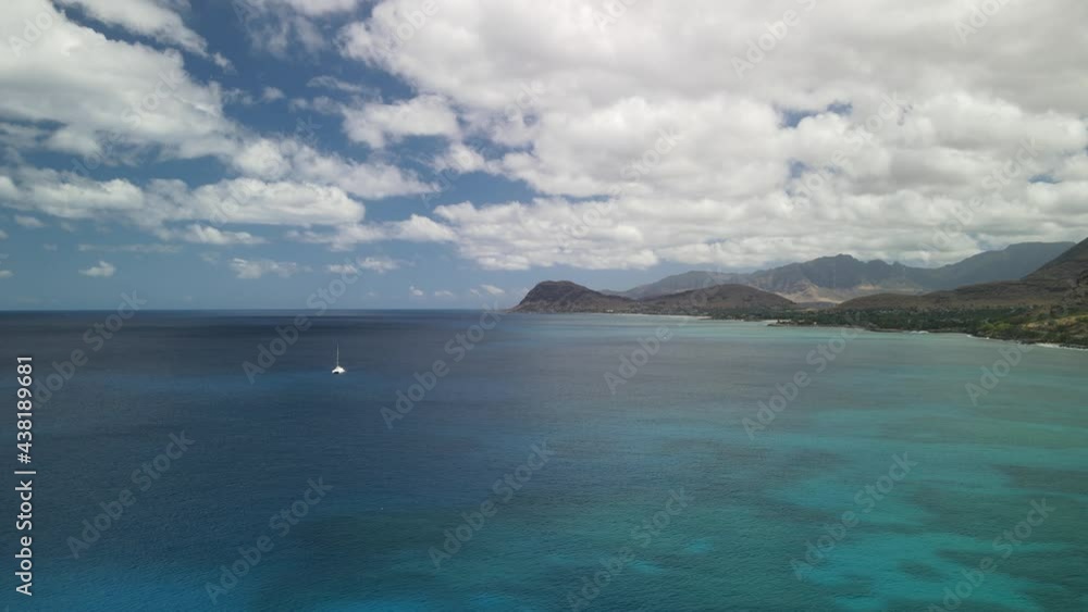 Slow moving aerial flying towards the mountains over the ocean with a boat in the scene Slow moving aerial flying towards the mountains over the ocean with a boat in the scene