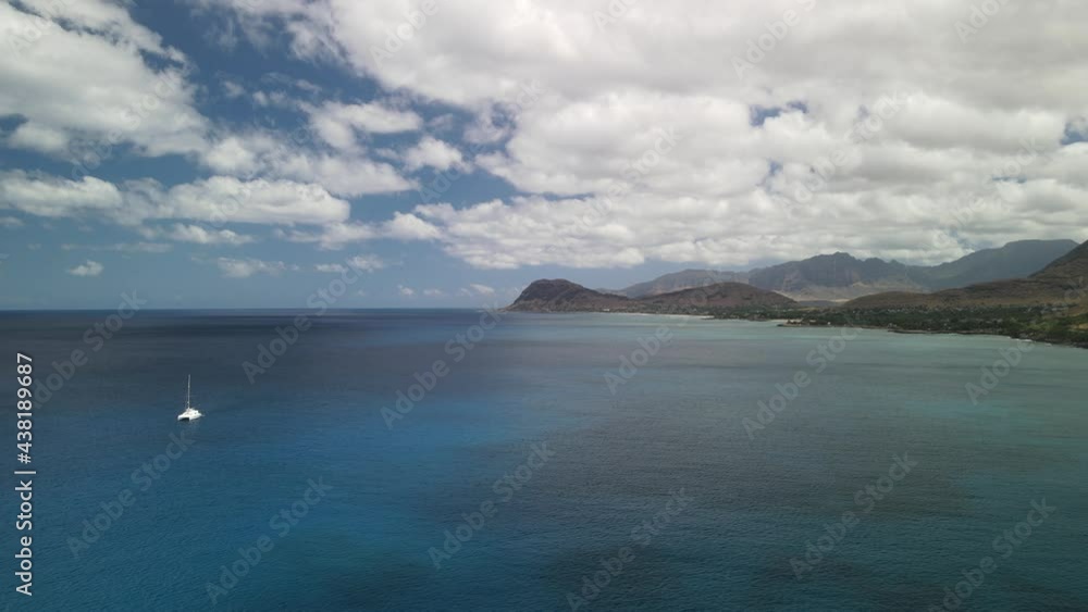 Slow moving aerial flying towards the mountains over the ocean with a boat in the scene Slow moving aerial flying towards the mountains over the ocean with a boat in the scene