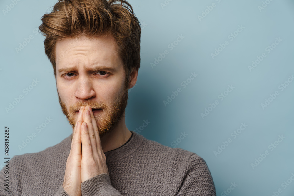 White ginger man frowning while holding palms together White ginger man frowning while holding palms together