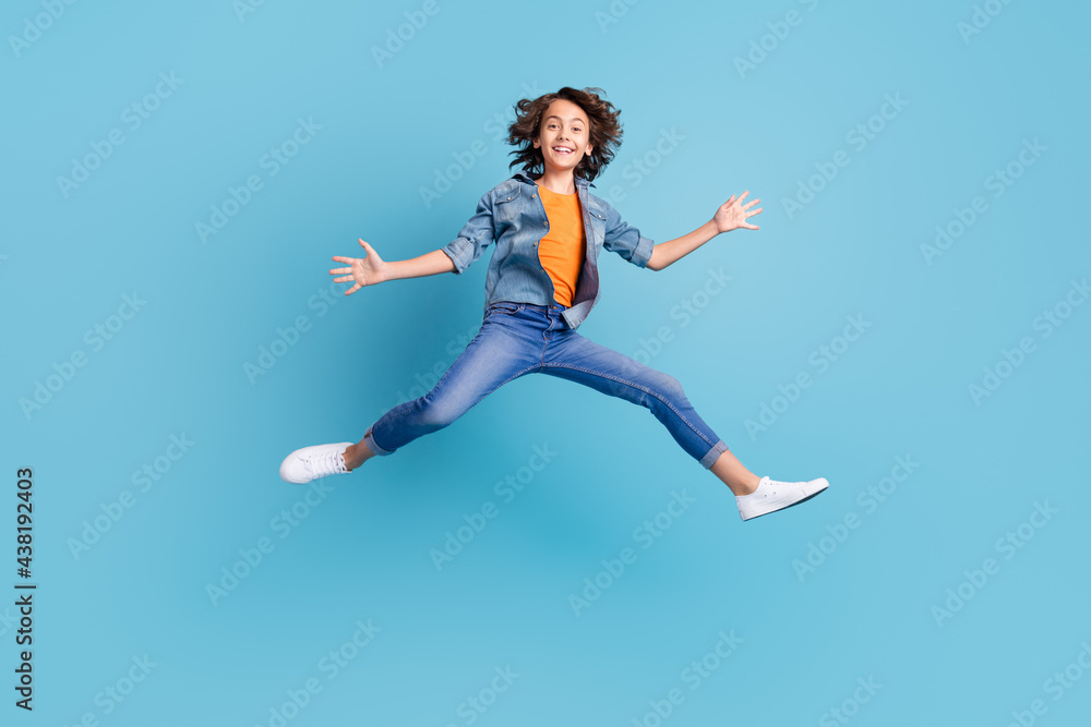 Full length photo of young excited boy happy positive smile jump show hands isolated over blue color background