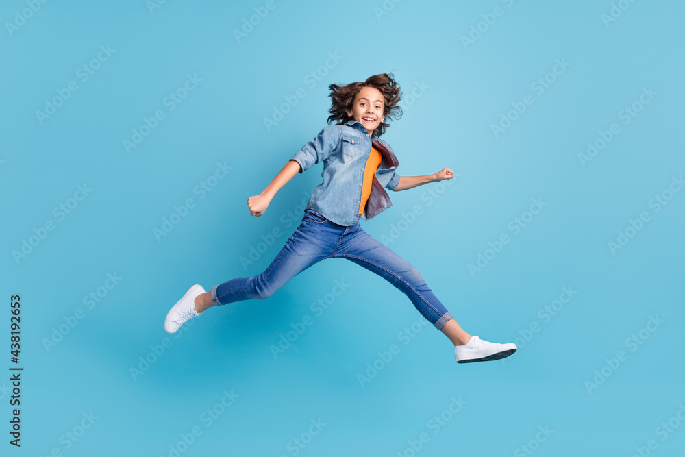 Full length profile side photo of young boy jump up go walk run isolated over blue color background Full length profile side photo of young boy jump up go walk run isolated over blue color background