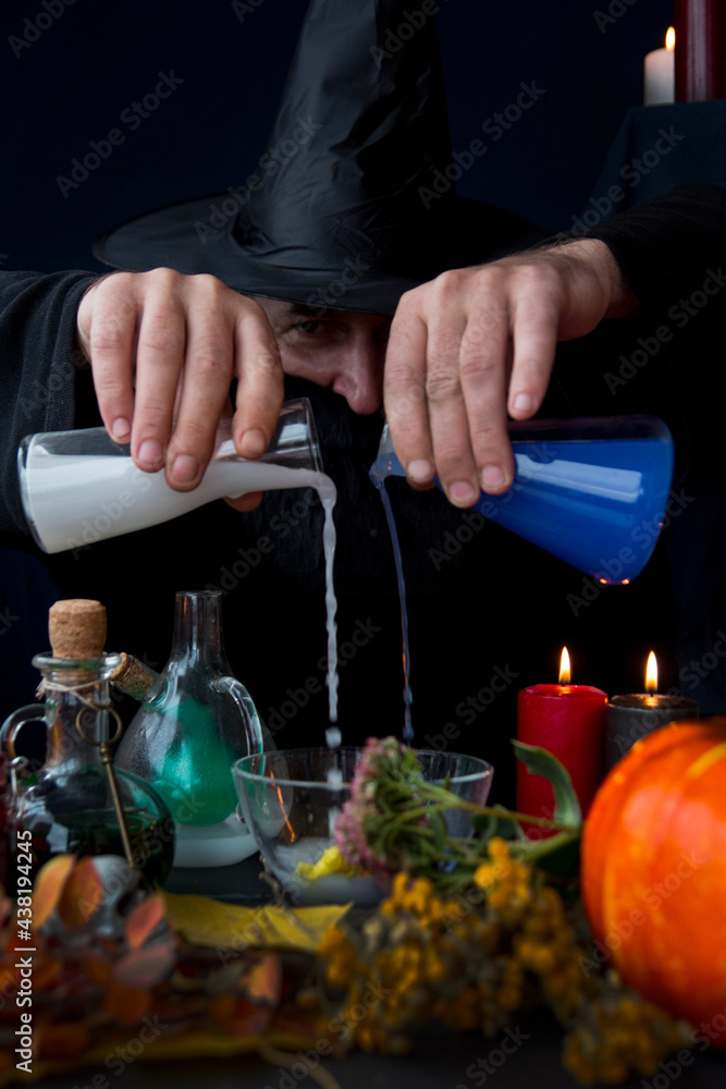 a male mage alchemist brews a potion. Halloween Holiday a male mage alchemist brews a potion. Halloween Holiday