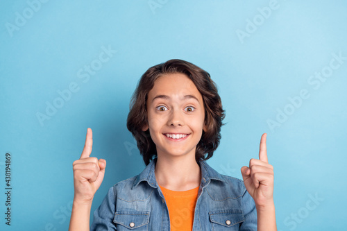 Photo of young school boy happy positive smile indicate fingers empty space ad advice choice isolated over blue color background