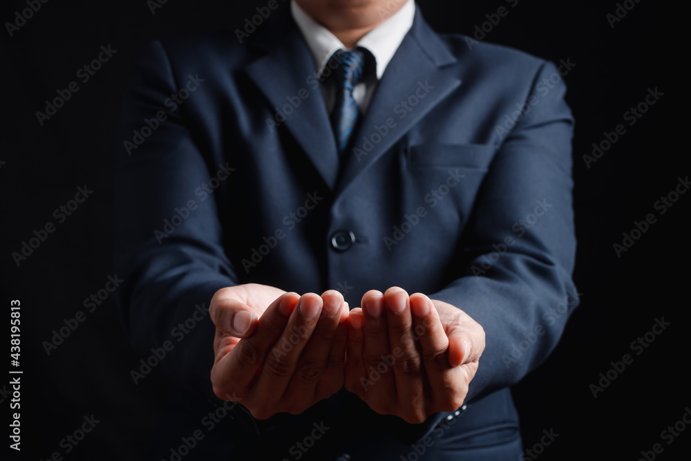 Close-up photo of a businessman in a suit on a black background, Businessman with an empty hand with copy space.