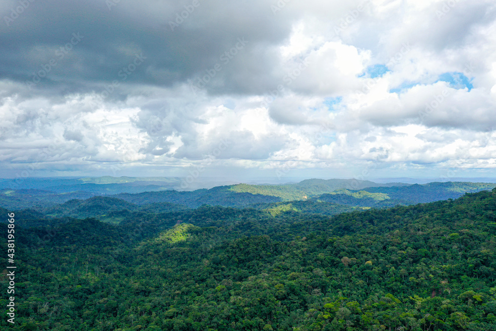 Aerial view over a tropical forest covered in rain clouds with sunlight falling through the cloudscape on the rainforest canopy in Ecuador South America