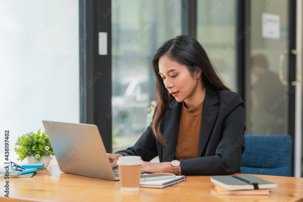 Charming Asian businesswoman sitting at the office using a laptop. Charming Asian businesswoman sitting at the office using a laptop.