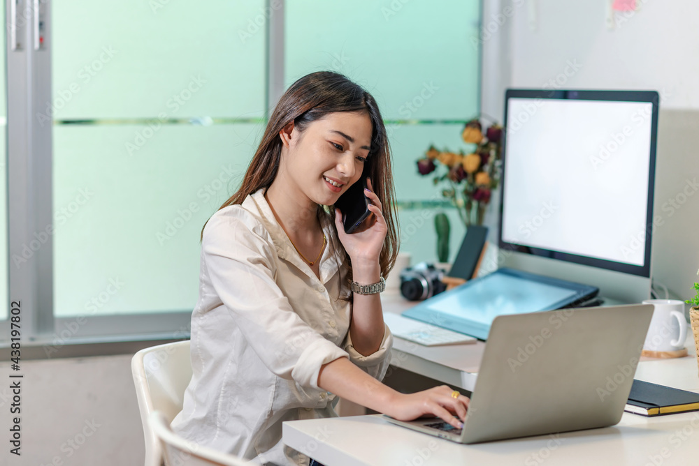 Asian businesswoman talking on the phone using a tablet at the office. Asian businesswoman talking on the phone using a tablet at the office.