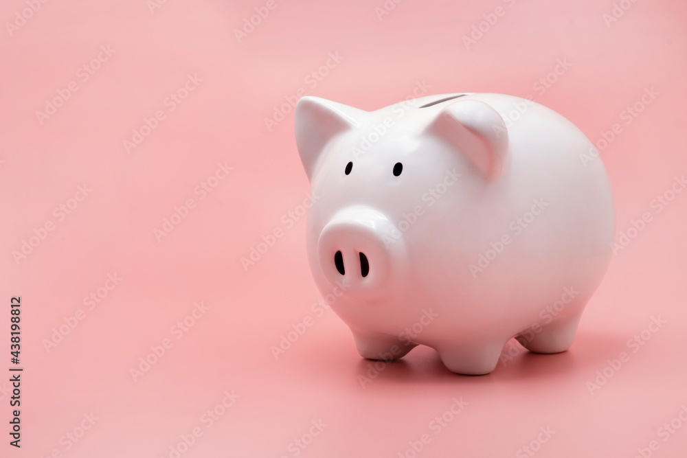 White piggy bank for money saving isolated on pastel pink background with copy space.