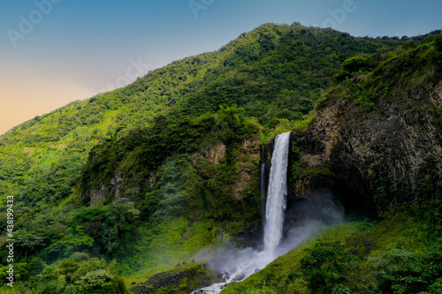 Background of a sideview of a beautifull waterfall in a mountain covered by trees during sunset photo