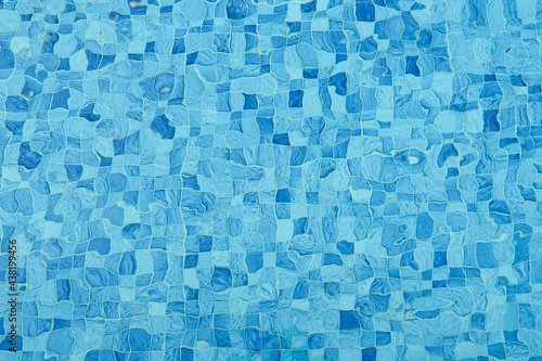 Top view of surface caustics ripped water in swimming pool and flow with waves background. Mosaic wall in blue color for copy space abstract backdrop.