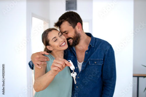Lovely caucasian couple in embrace showing keys of their new home.