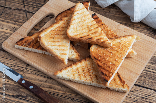 Slices of crispy bread toast for sandwiches on a cutting board, wooden rustic background. Close up.