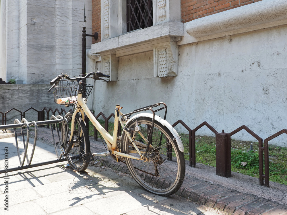Ferrara, Italy. An old bicycle without a saddle abandoned in the bicycle rack of the Central Post Office.