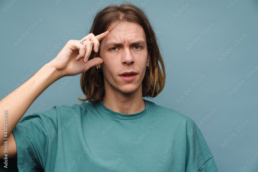 Young white man with headache frowning while holding his head Young white man with headache frowning while holding his head